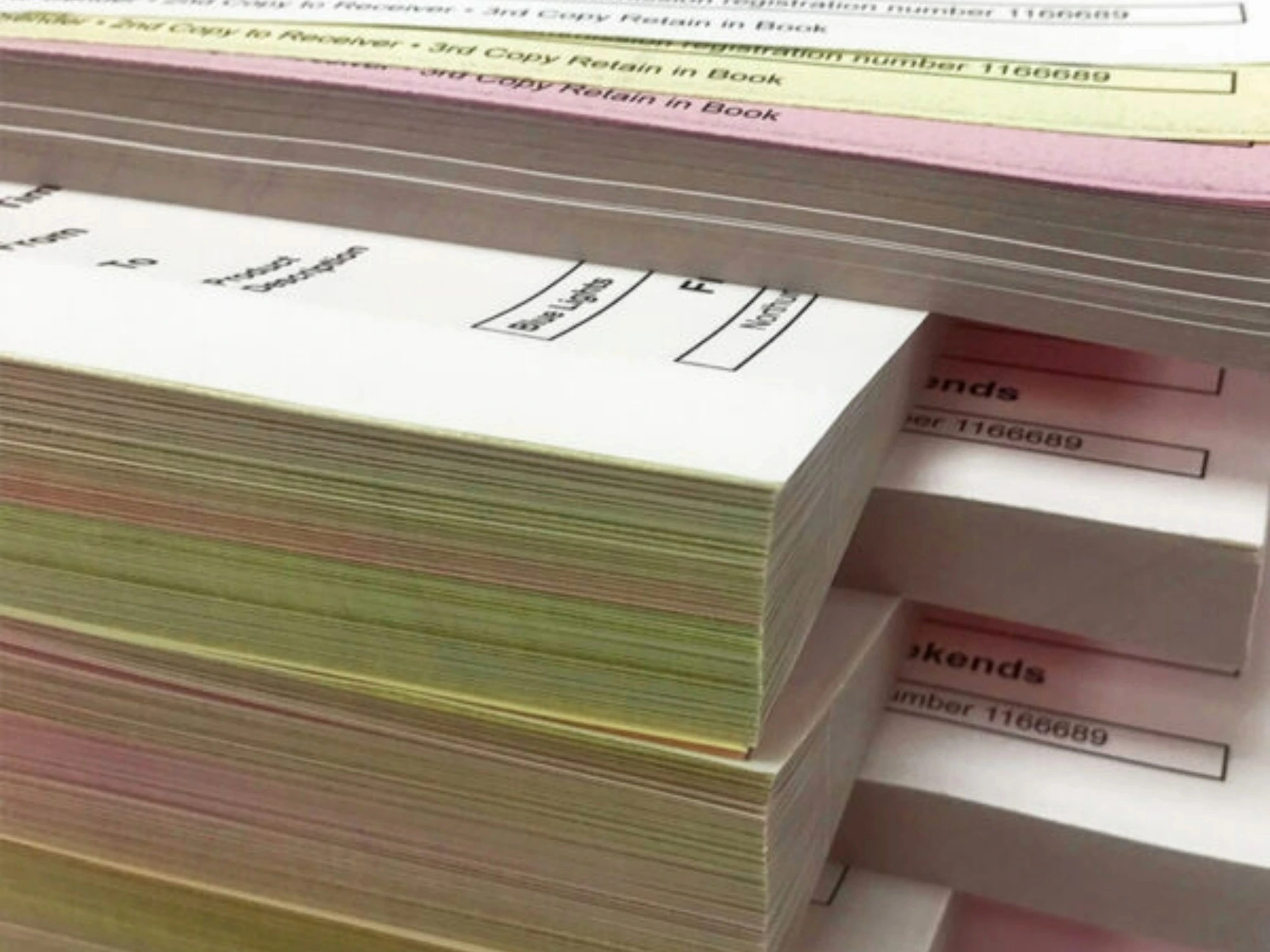 Stack of custom-printed NCR pads with coloured carbonless paper layers.