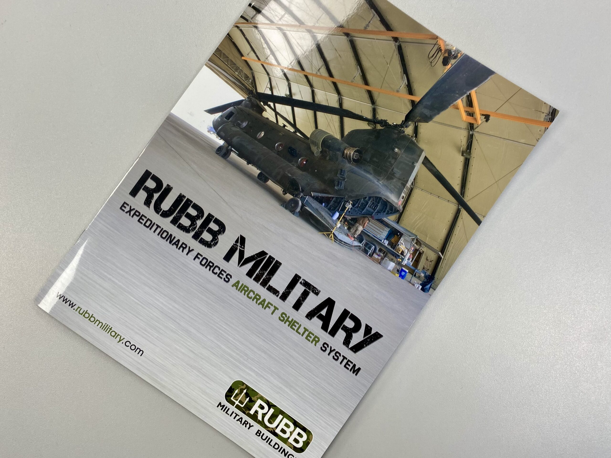Rubb Military glossy brochure front cover, showing a photograph of a modern aircraft shelter.
