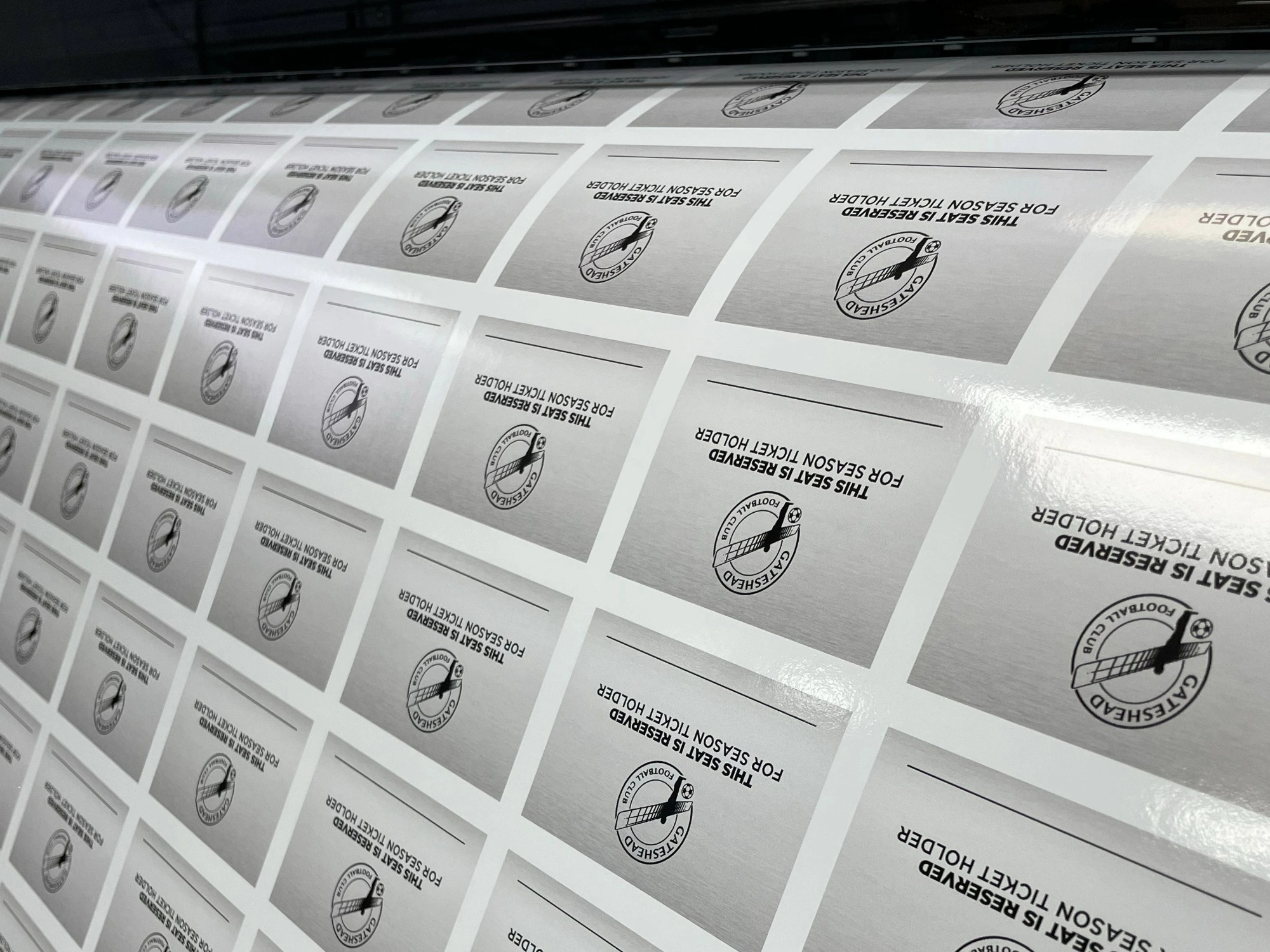 A large page of grey Gateshead Football Club reserved seat stickers, fresh from the printer.